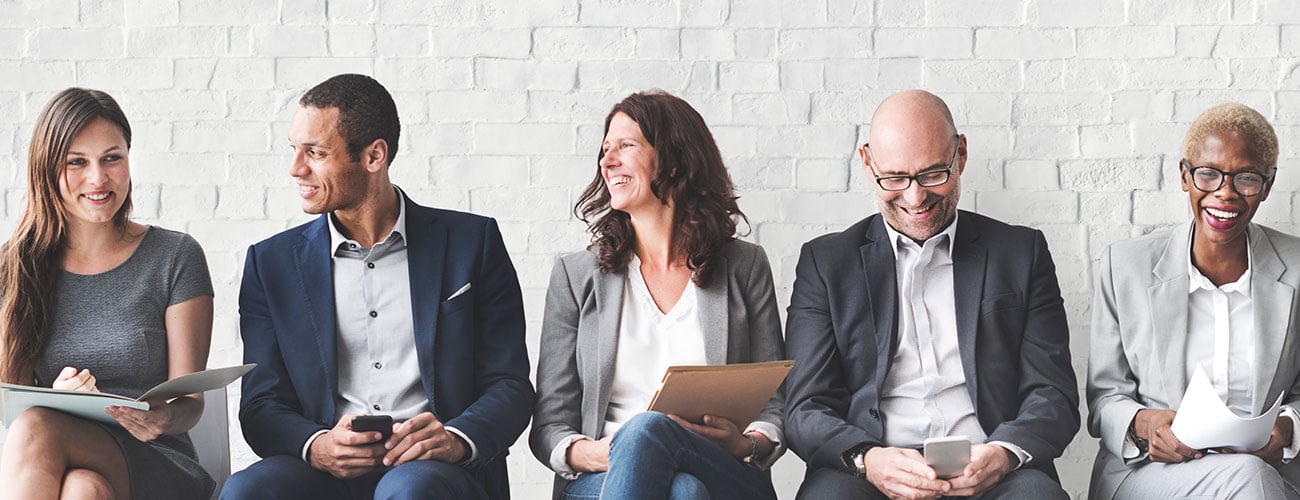 5 people sitting in a row smiling and laughing